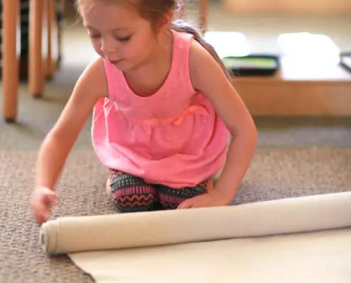 3K4A3073 a child using Montessori knobbed cylinders to refine visual discrimination