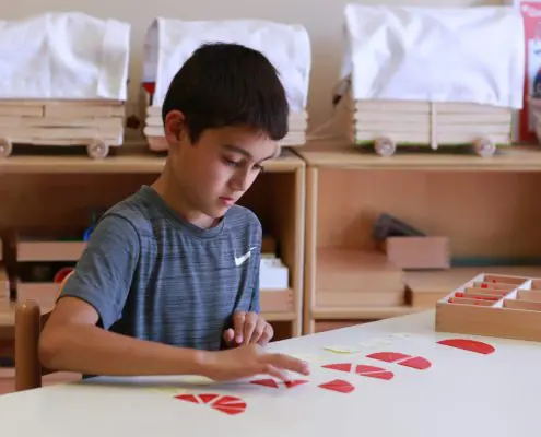 3K4A6546 a child focused on Montessori pink tower blocks, learning size relationships